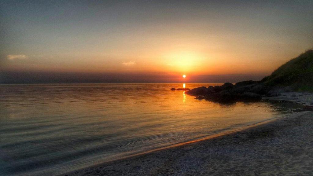 a sunset on a beach with the sun setting at Apart-Hotel Onegin & Thermal Zone in Sozopol