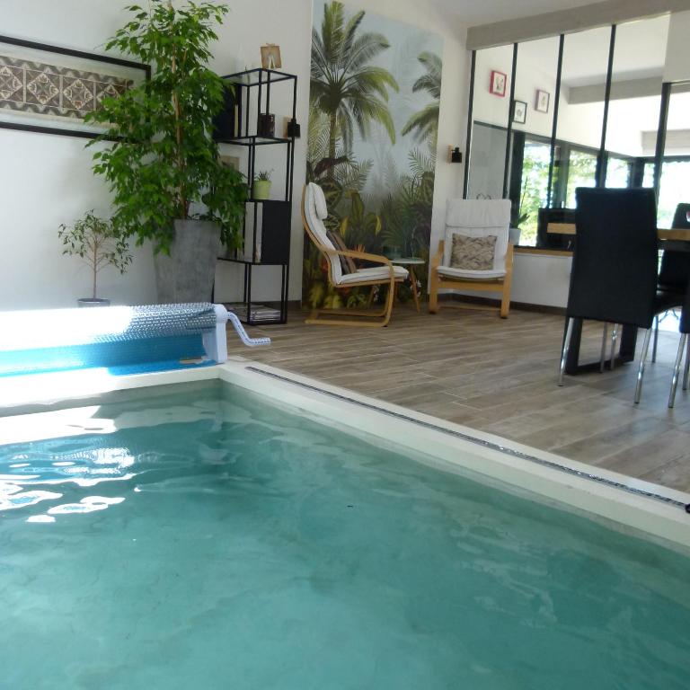 - un salon avec une piscine, une table et des chaises dans l'établissement Chambre d'hôtes du Pilou, à Queyssac-les-Vignes