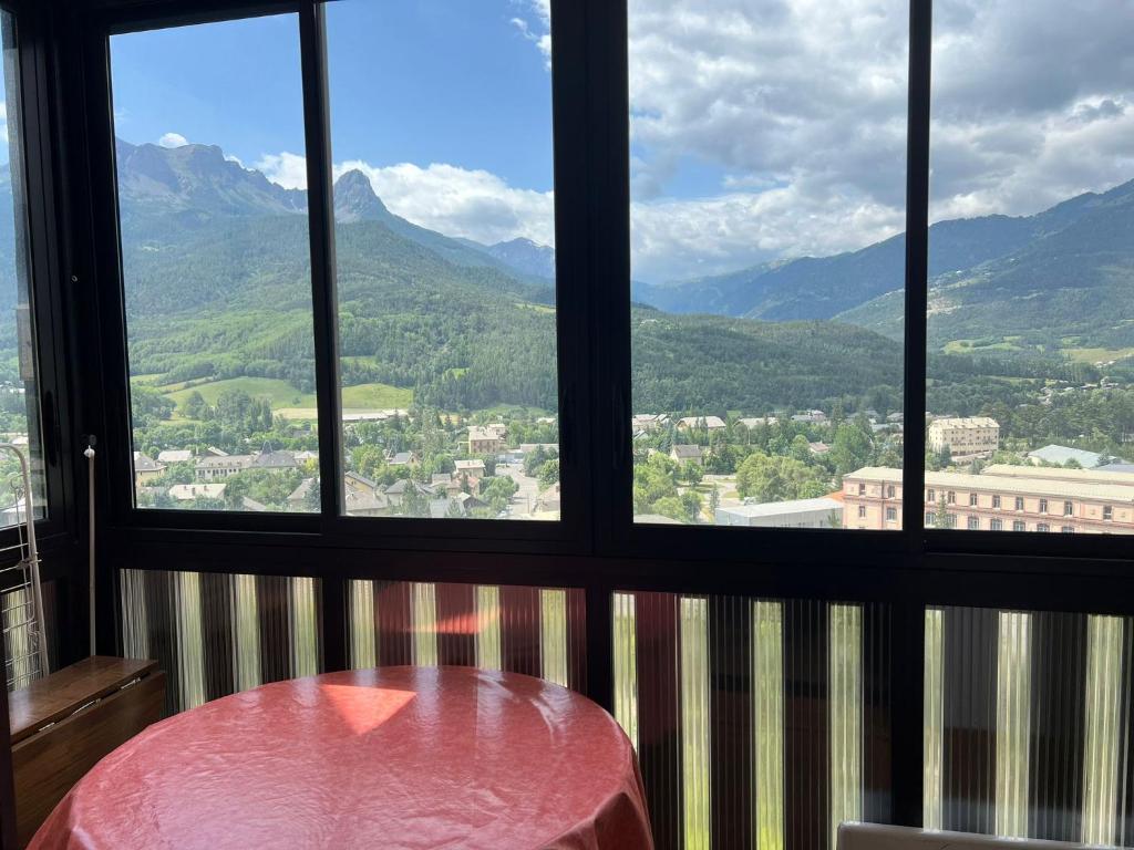 a room with a table and a view of mountains at Terrasse de l'Adroit - Barcelonnette - Wi-fi gratuit in Barcelonnette