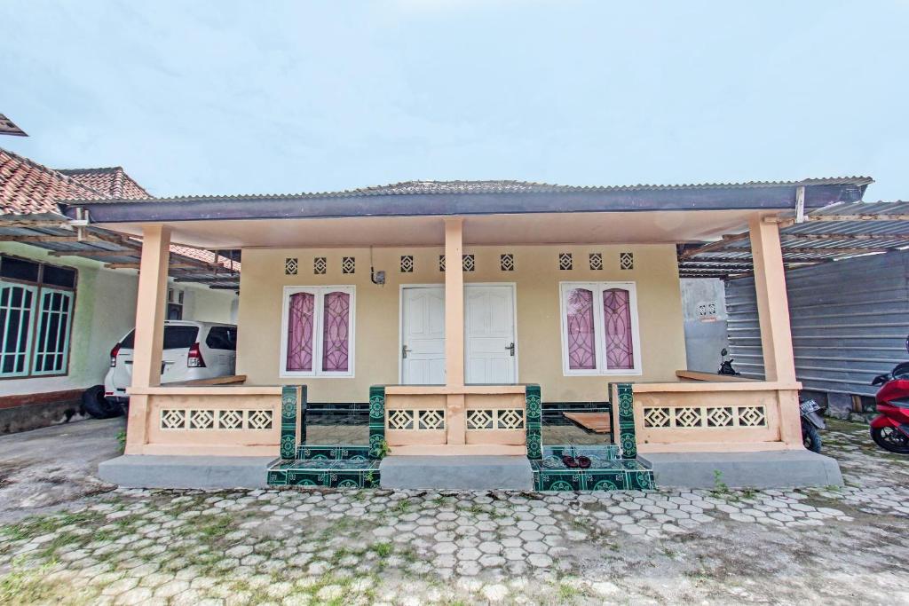 a yellow house with two benches in front of it at Hotel O Zahira Homestay Near Ekas Surf School and Service in Ekas