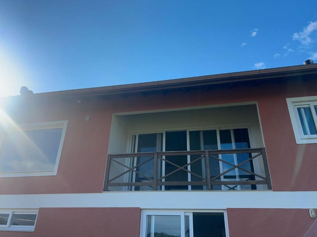 a house with a balcony with the sun shining on it at Casa em condomínio rural in Rancho Queimado