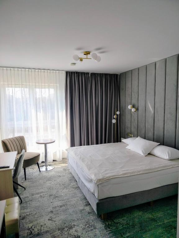 a bedroom with a bed and a desk and a table at Hotel Sokołowska Airport Modlin in Nowy Dwór Mazowiecki