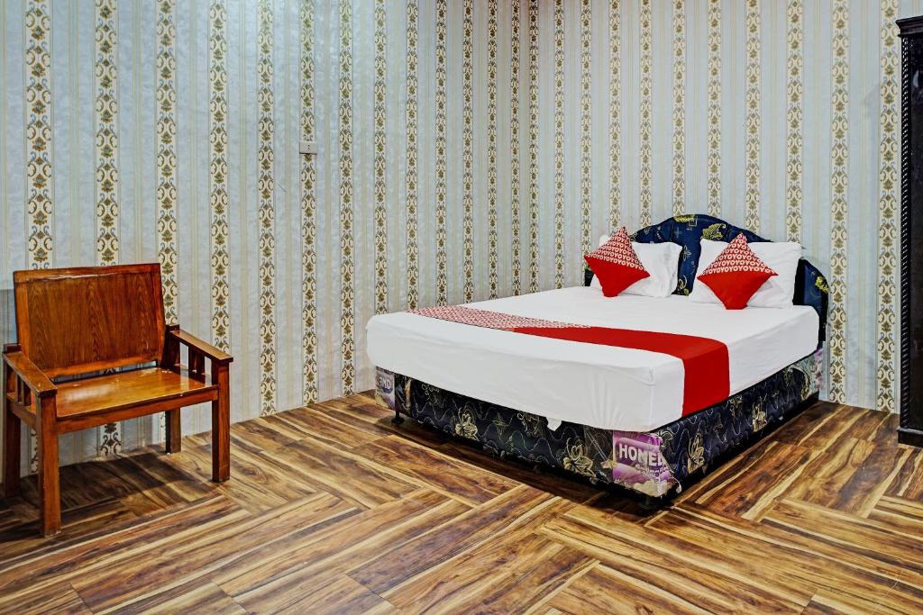 een slaapkamer met een bed, een stoel en een bureau bij Hotel O Taman Wisata Iman Ii Near Taman Wisata Iman Sitinjo in Hutamanik