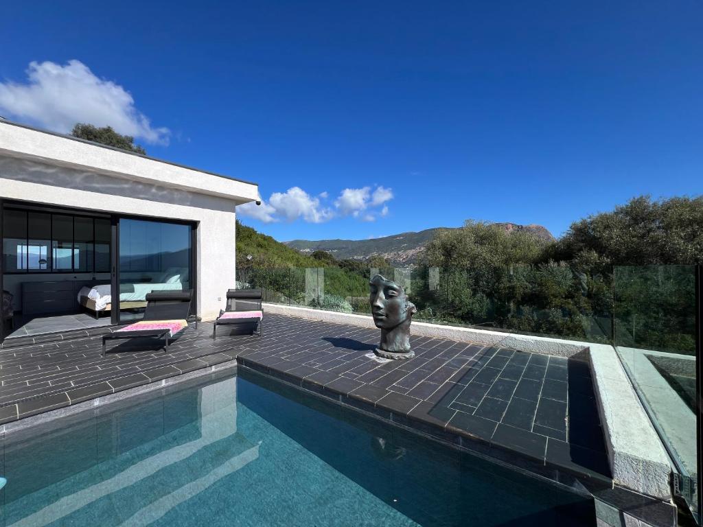 - une piscine avec une statue à côté d'une maison dans l'établissement Villa Panoramique, à Alata