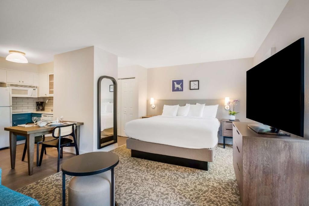 バンクーバーにあるSonesta ES Suites Portland Vancouver 41st Streetの大きなベッドとキッチンが備わるホテルルームです。