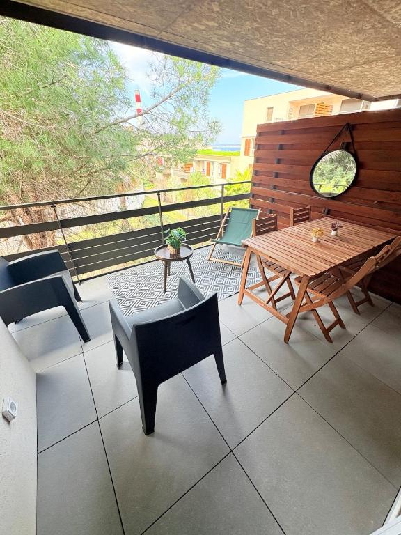 d'une terrasse avec une table et des chaises en bois sur un balcon. dans l'établissement Élégant et cosy T3 neuf, parking, à Sète