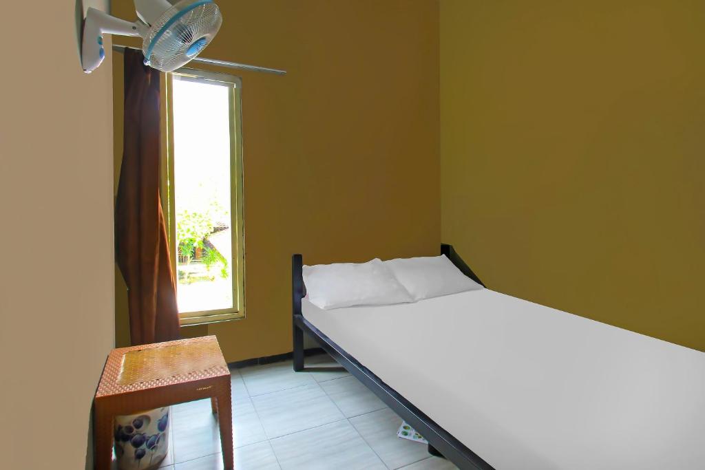 a bedroom with a bed and a window and a chair at OYO 92308 Kos Duduk in Lajor