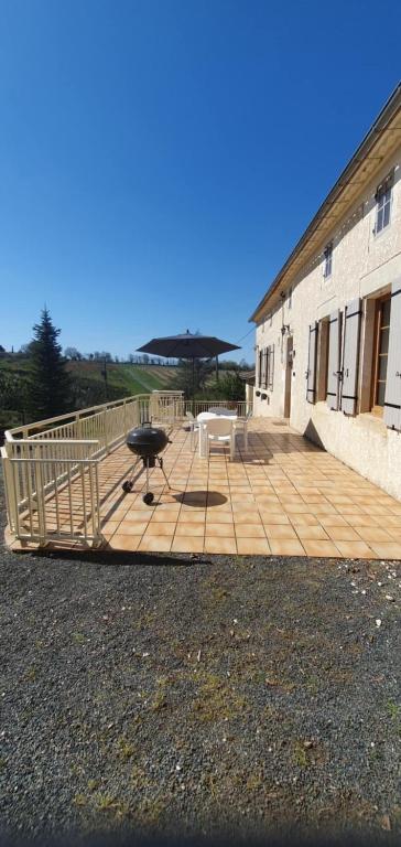 un grand patio avec un grill et un bâtiment dans l'établissement maison 2 chambres au calme, à Saint-Bonnet-sur-Gironde