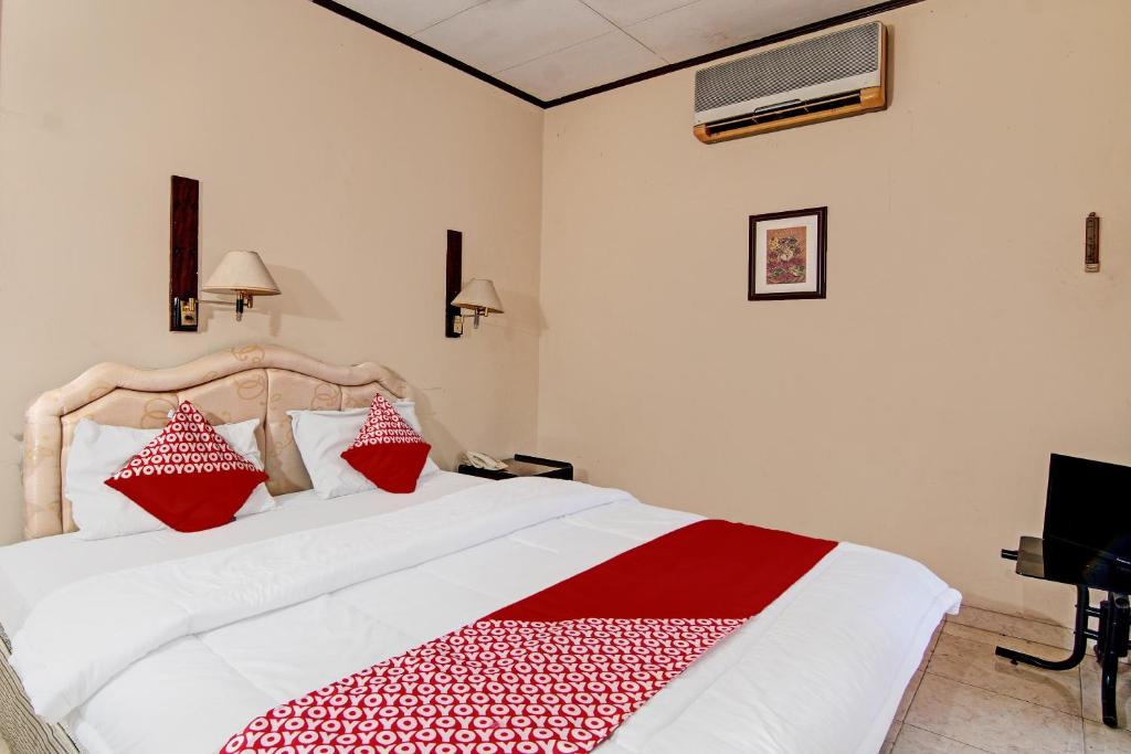 Un dormitorio con una cama con almohadas rojas y blancas. en Hotel O Rindu Sempadan Near Taman Wisata Rindu Sempadan, en Pekanbaru