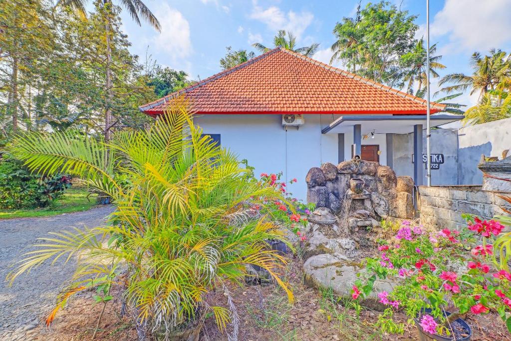 a small white house with an orange roof at Hotel O Mustika in Mendaya