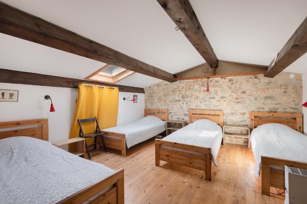 Cette chambre comprend 3 lits et un mur en pierre. dans l'établissement Gîte de La Tour, à Saint-Guilhem-le-Désert