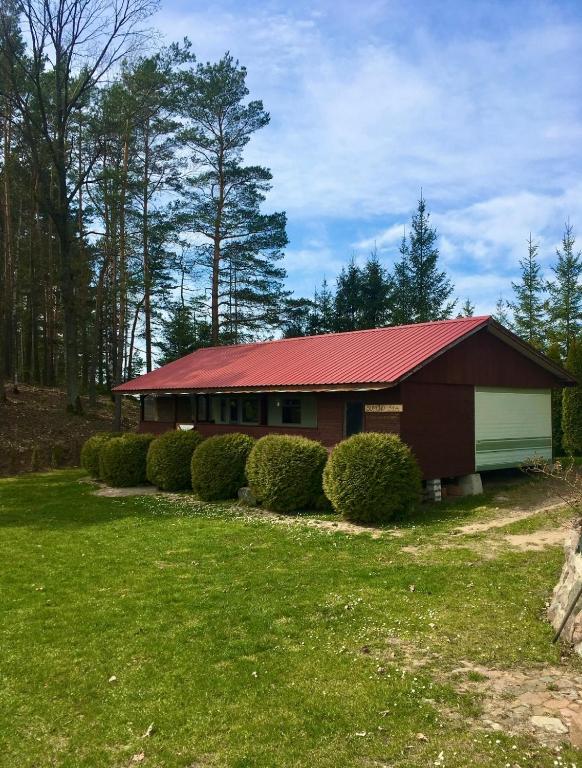 a red house with a red roof and some bushes at Kalva Sumowo in Sumowo