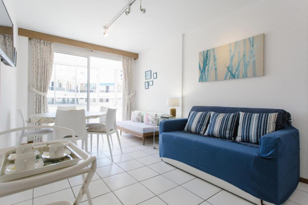 Una sala de estar con un sofá azul y una mesa. en Punta! Bem localizado e completo!, en Punta del Este