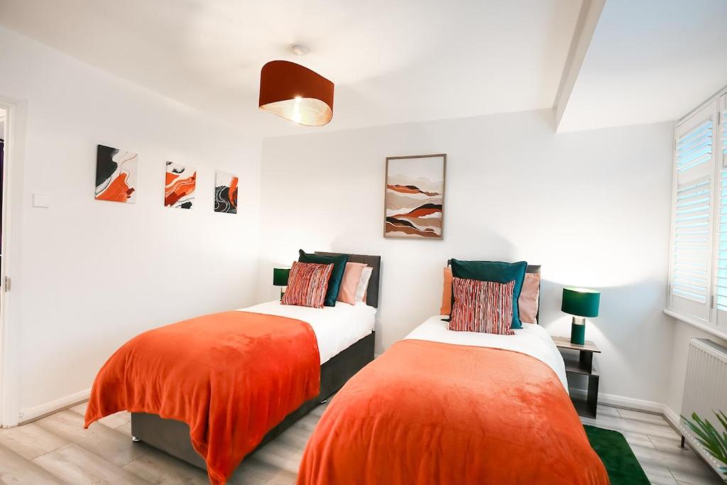 two beds in a room with white walls and orange sheets at 2BR Near Tottenham Stadium - WiFi - Free Parking in Ponders End