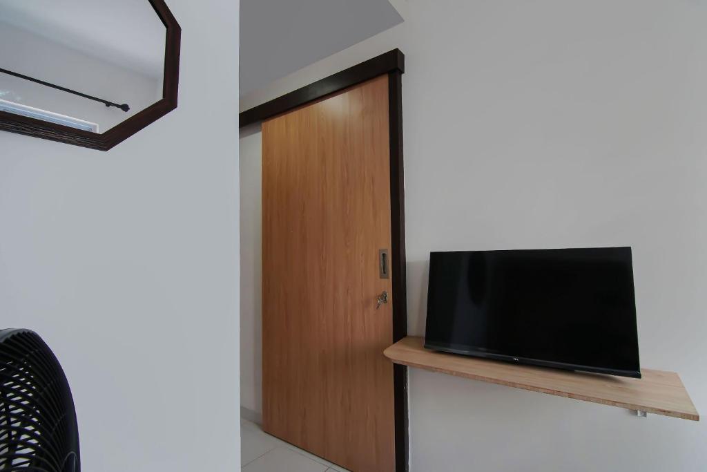 a room with a door and a television on a shelf at Hotel O Pondok Melati Syariah in Pekanbaru