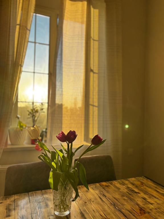 a vase with flowers on a table in front of a window at ELAY Apartments in Baku