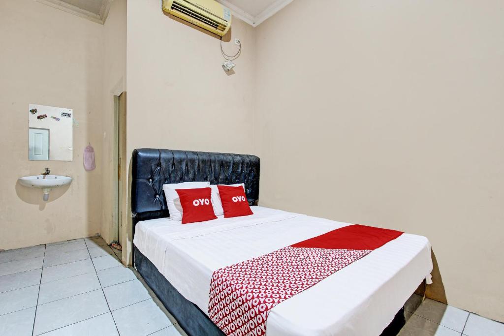 a bedroom with a bed with red pillows and a sink at OYO 92459 Cahyo Kost 2 in Semarang