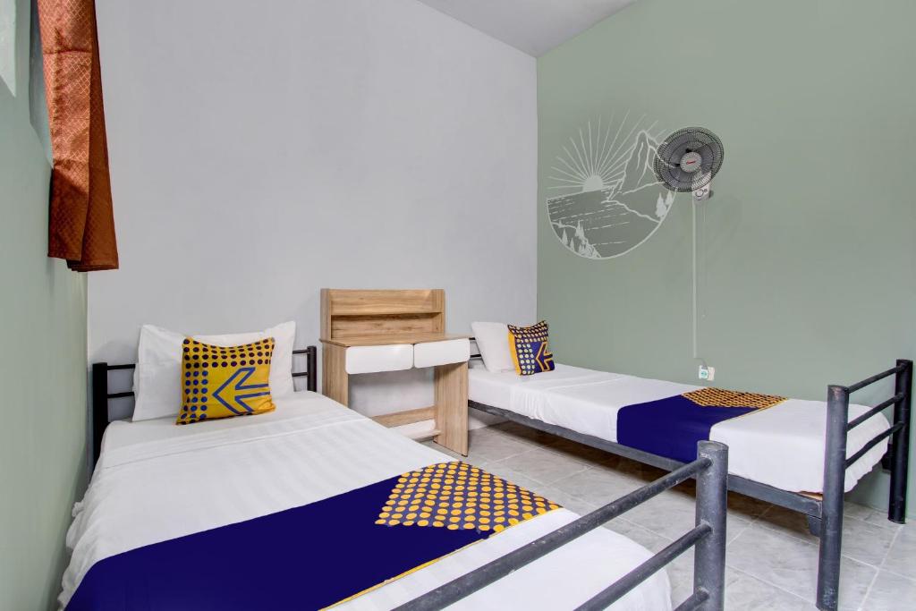 a room with two beds and a fan at SPOT ON 92490 Casa Homestay Syariah in Brangsong