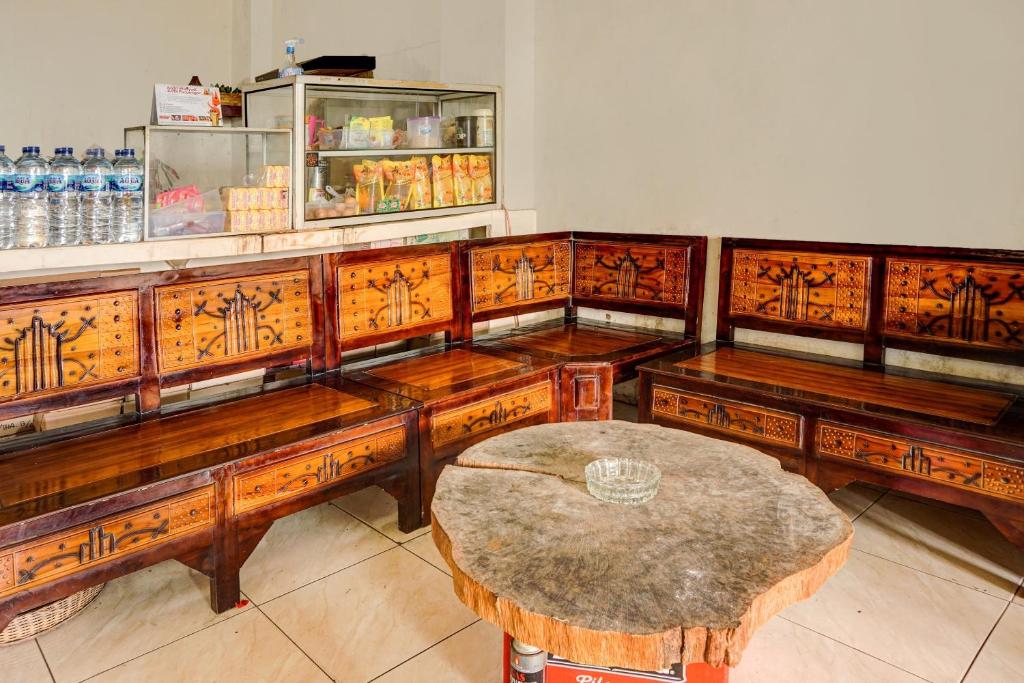a group of wooden benches with a table in a room at OYO Life 92499 Bagas Homestay Wonokitri in Pasuruan