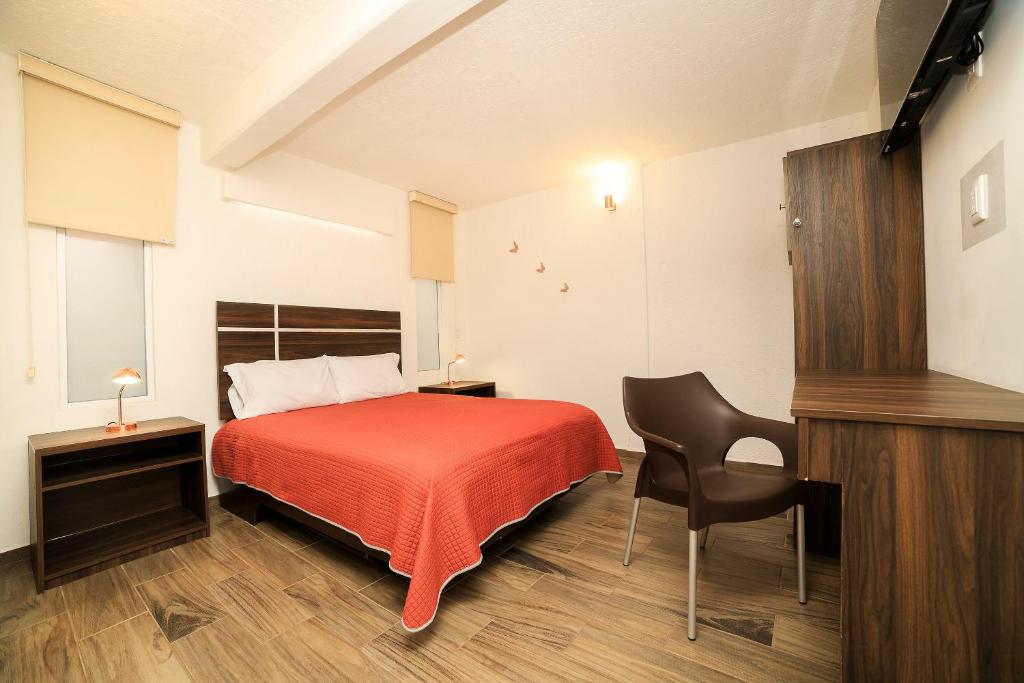 a bedroom with a red bed and a black chair at Capital O Hotel Boutique Las Torres in Tlaxcala de Xicohténcatl