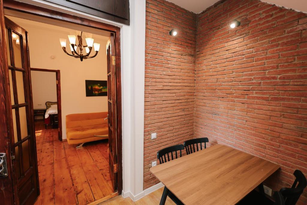 een eetkamer met een bakstenen muur en een houten tafel bij Rezis sweet home in Tbilisi City