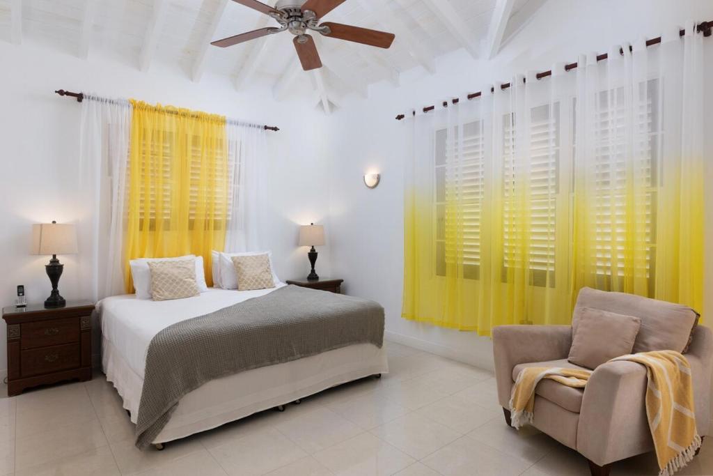 ein Schlafzimmer mit einem Bett und einem Stuhl und einem Deckenventilator in der Unterkunft Refreshing 2bed Townhome walking distance to beach in Saint James
