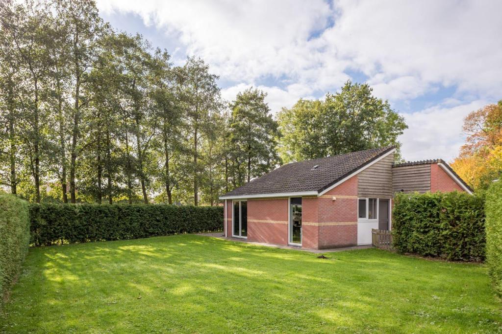 a red brick house with a large yard at Holiday Home Garden View in Tzummarum