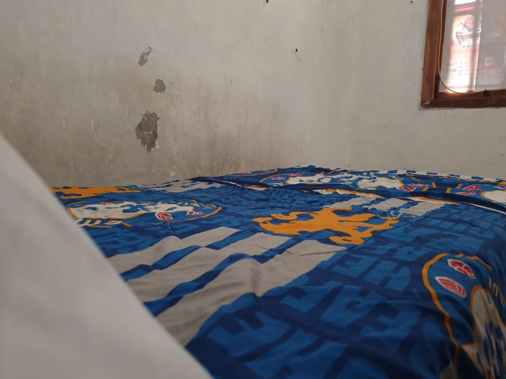 a bed with a blue and orange comforter on it at OYO Life 92620 Syfa Kost in Malang