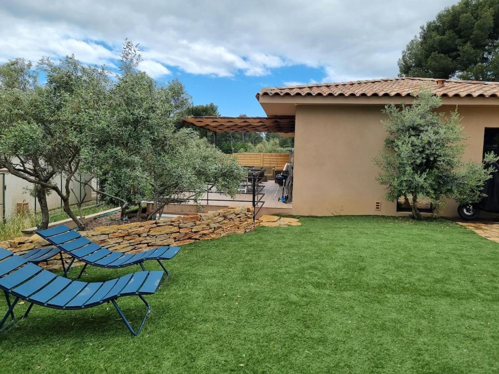 2 chaises bleues assises sur une pelouse dans une cour dans l'établissement Villa Les Aludes, aux Lecques