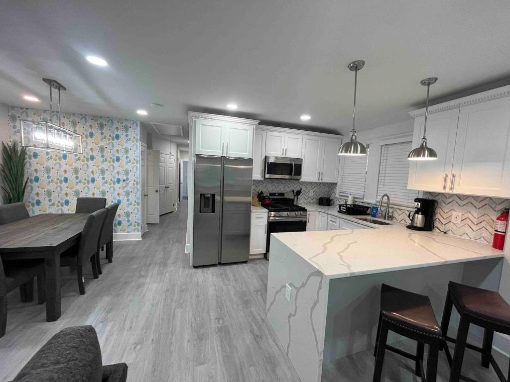 cocina con armarios blancos y mesa y cocina con comedor en Bungalow Way-Close to all w/ Pool Table & Games, en Atlantic City
