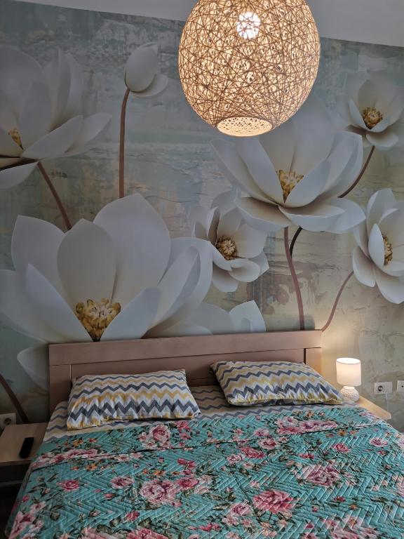 a bedroom with a bed with white flowers on the wall at Vacation Apartment City Kvart in Podgorica