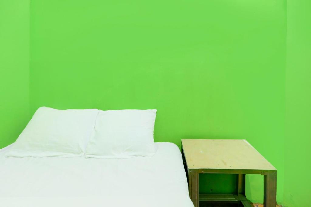 un lit avec une table à côté d'un mur végétal dans l'établissement Hotel O Joyoakis 2 Homestay SyariahNearMall Nagoya Hill, à Nagoya