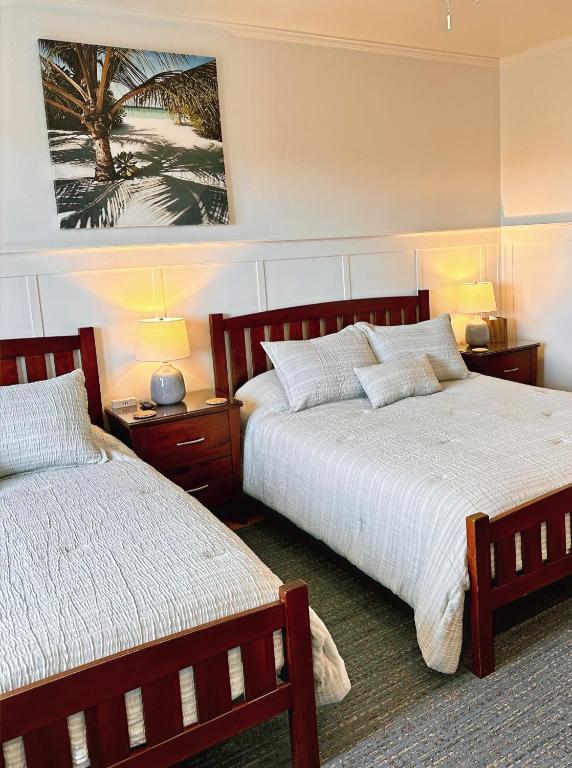 a bedroom with two beds and a painting on the wall at Hilo Town Inn in Hilo