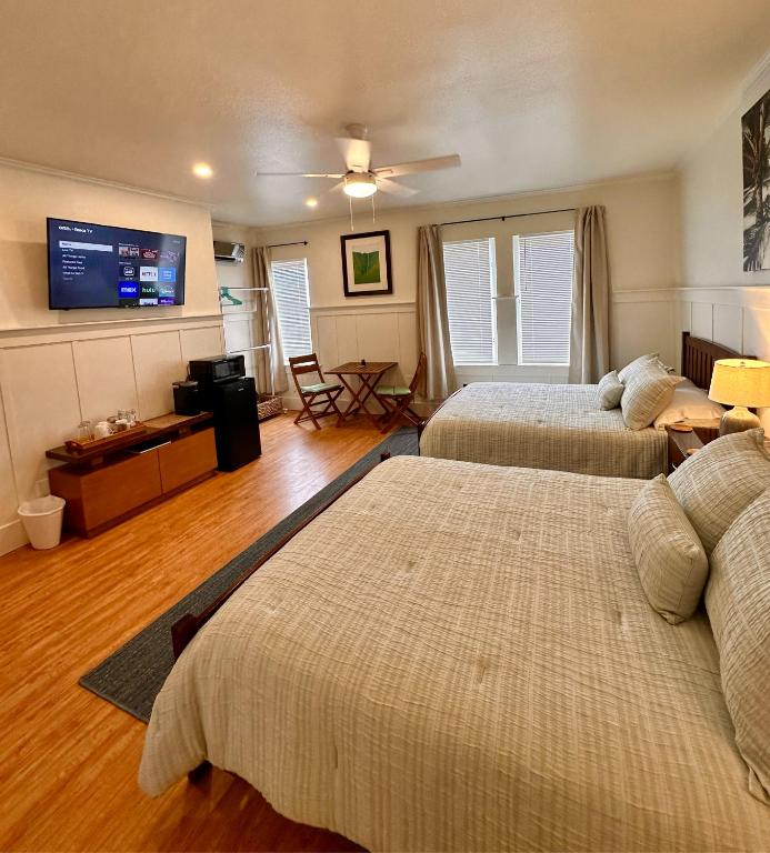 a bedroom with two beds and a flat screen tv at Hilo Town Inn in Hilo