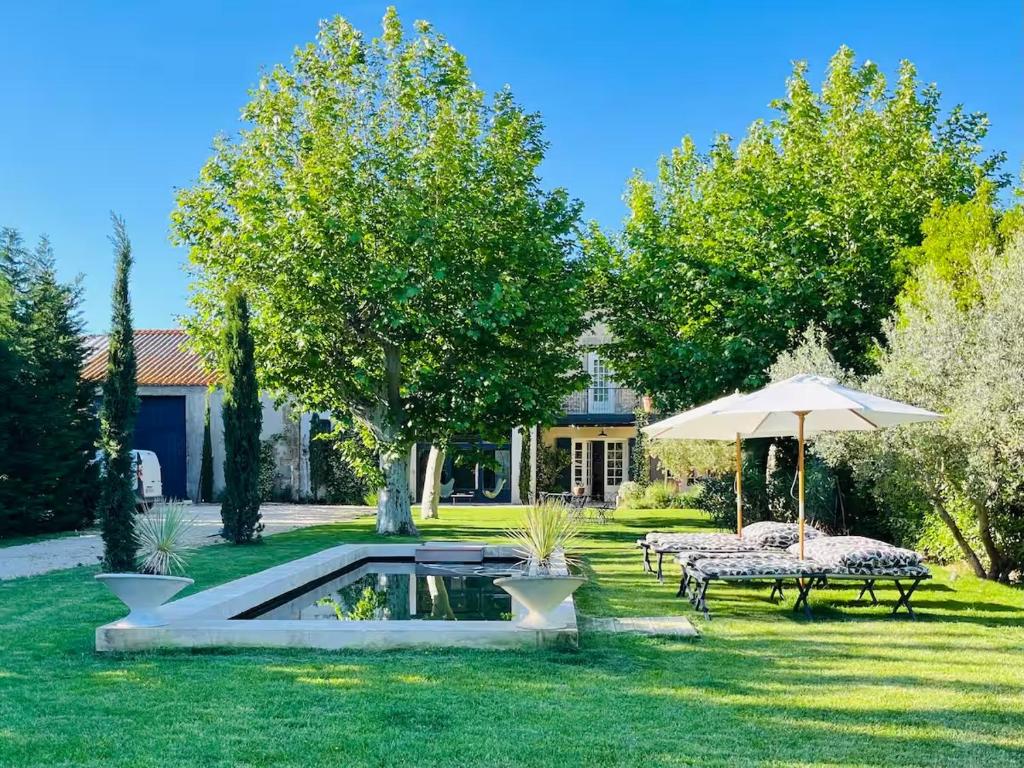 - un jardin avec 2 tables et un parasol dans l'établissement Mas Sylvestre Exceptional Stay in Provence, à Fontvieille