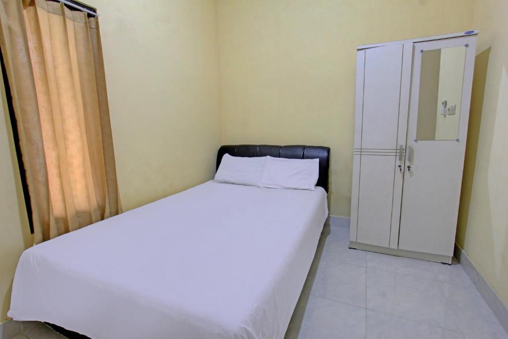 a bedroom with a large white bed and a closet at Hotel O Kos Moncok in Tjakranegara