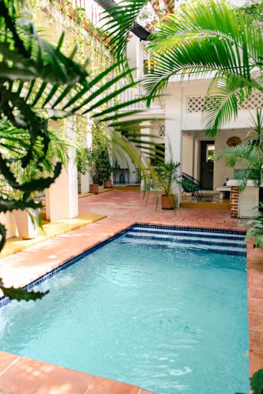 a swimming pool in the middle of a courtyard with palm trees at Casa Guerrero in Cartagena de Indias