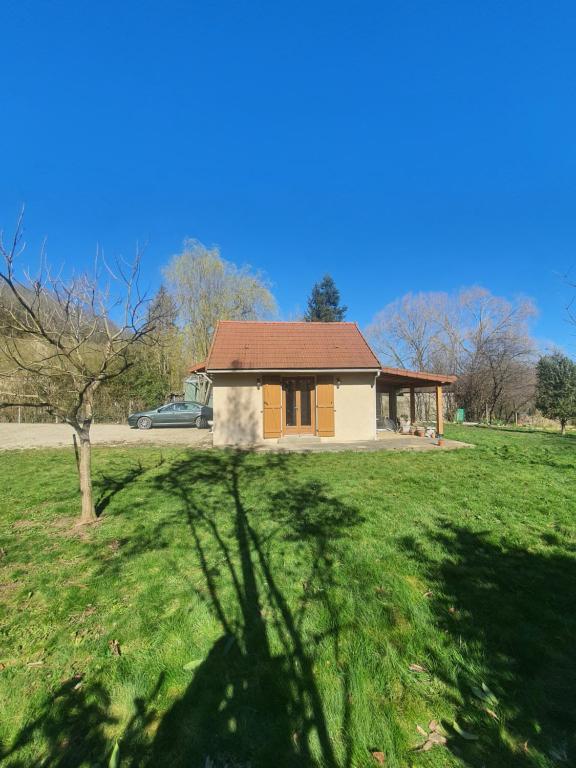 une petite maison dans un champ avec un arbre dans l'établissement La maisonnette, à Saint-Père