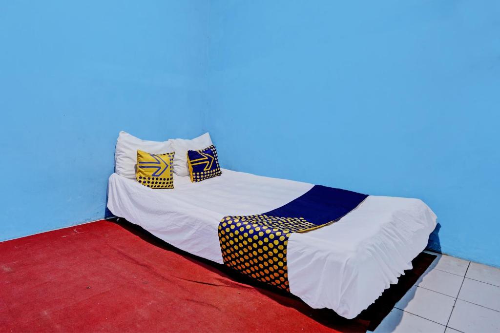 a bed with three pillows on it in a room at Hotel O Lestari Syariah in Sidoarjo