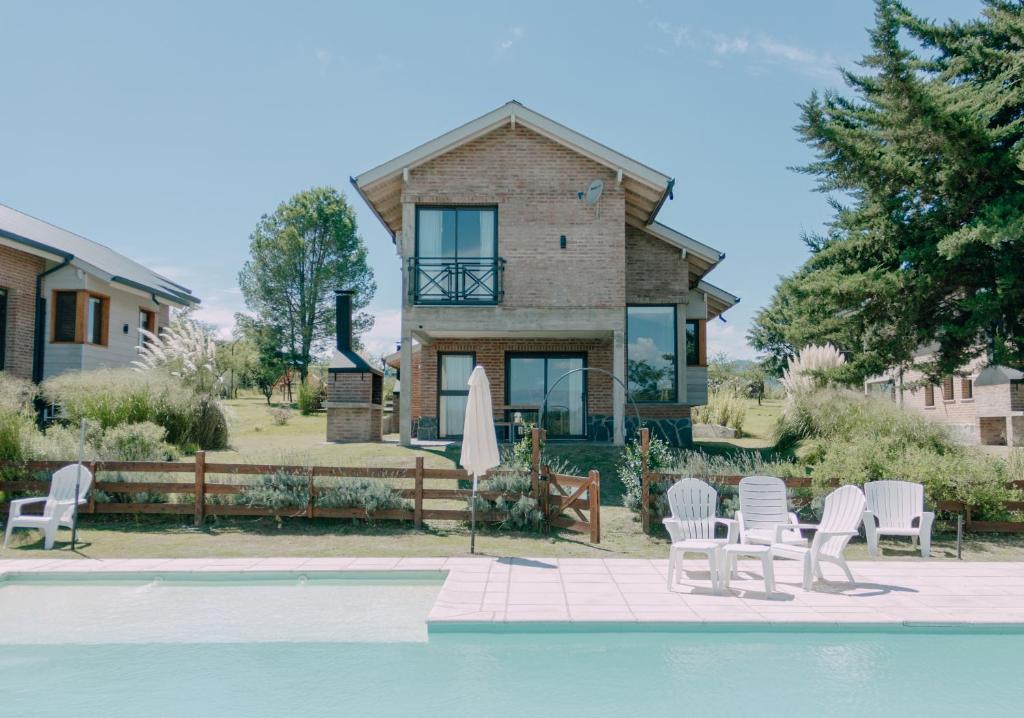 a house with a pool in front of a house at Pentagrama, casas de campo in Villa General Belgrano