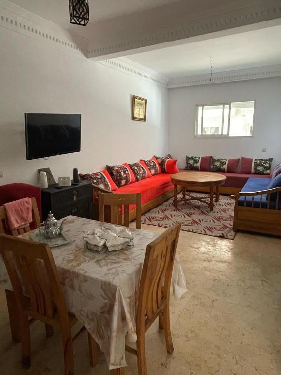 a living room with a table and a red couch at Sabah Appartment in Essaouira