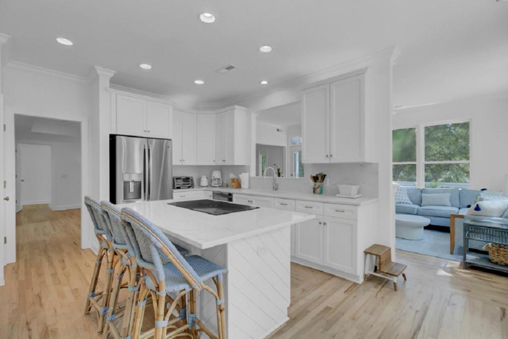 una cocina con armarios blancos y una isla de cocina con sillas en Fairway Oaks 33 by Wild Dunes, with Amenities, en Isle of Palms