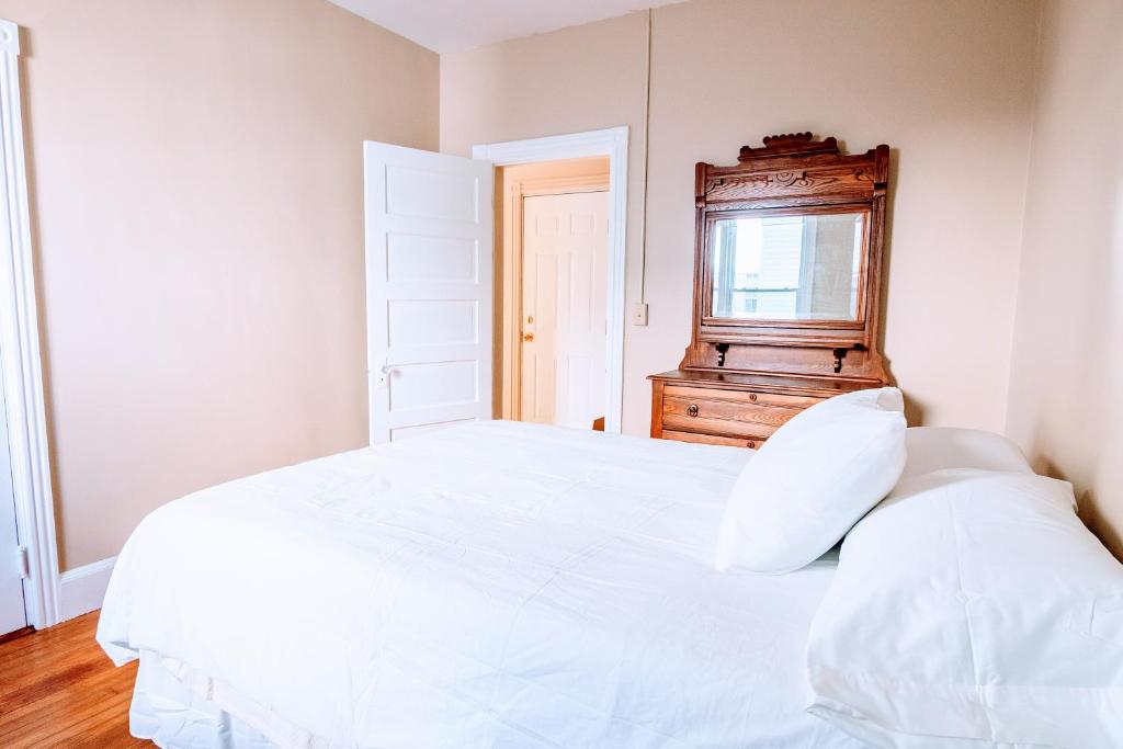 a bedroom with a white bed and a dresser at Spotless Victorian on William in Portland