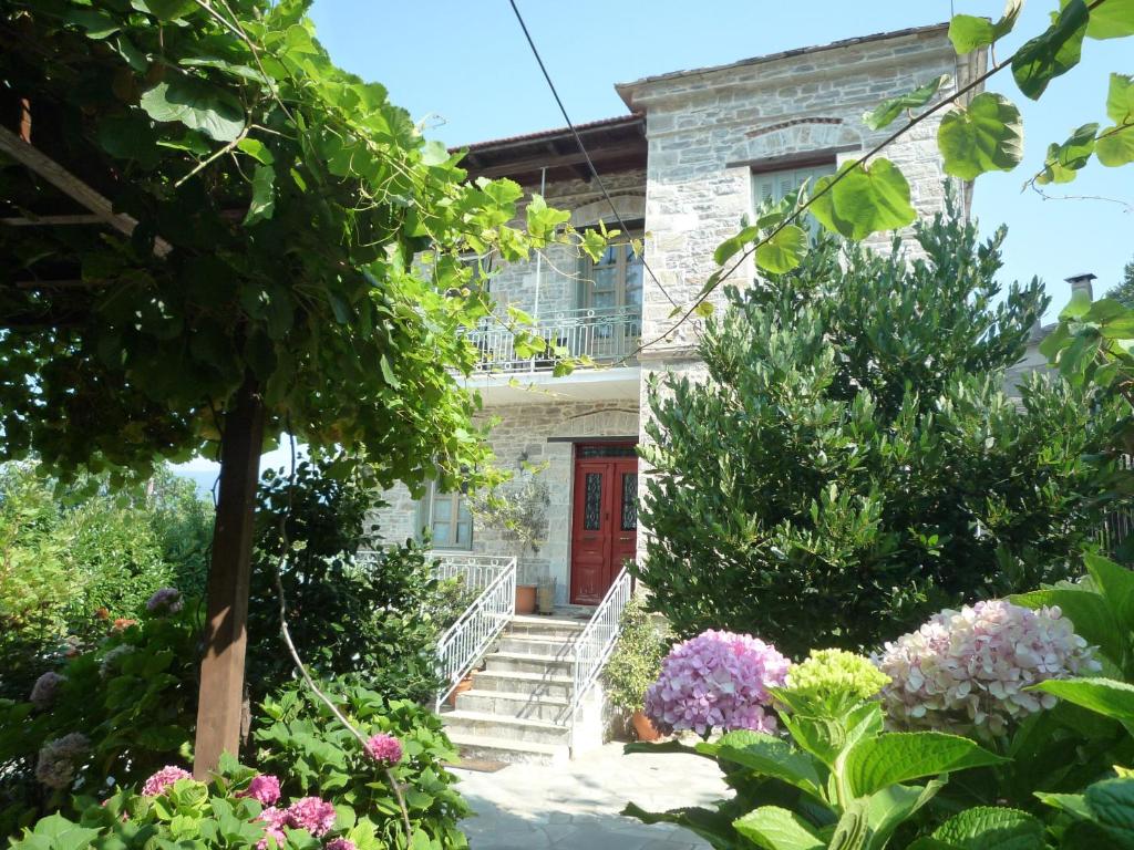 una casa con una puerta roja y algunas flores en Arhontiko Prepala en Neochori