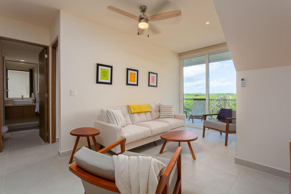 a living room with a white couch and a ceiling fan at Luxurious penthouse by the beach in Akumal