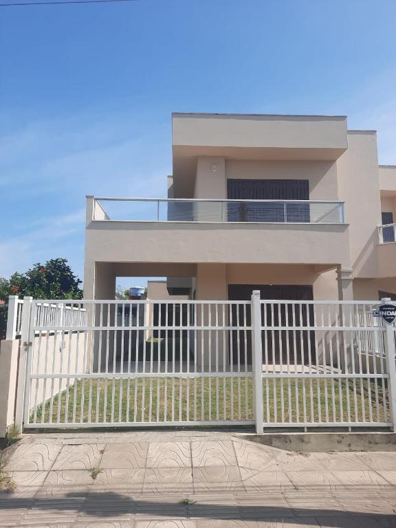 a house with a white fence in front of it at Casa de férias in Arroio do Sal