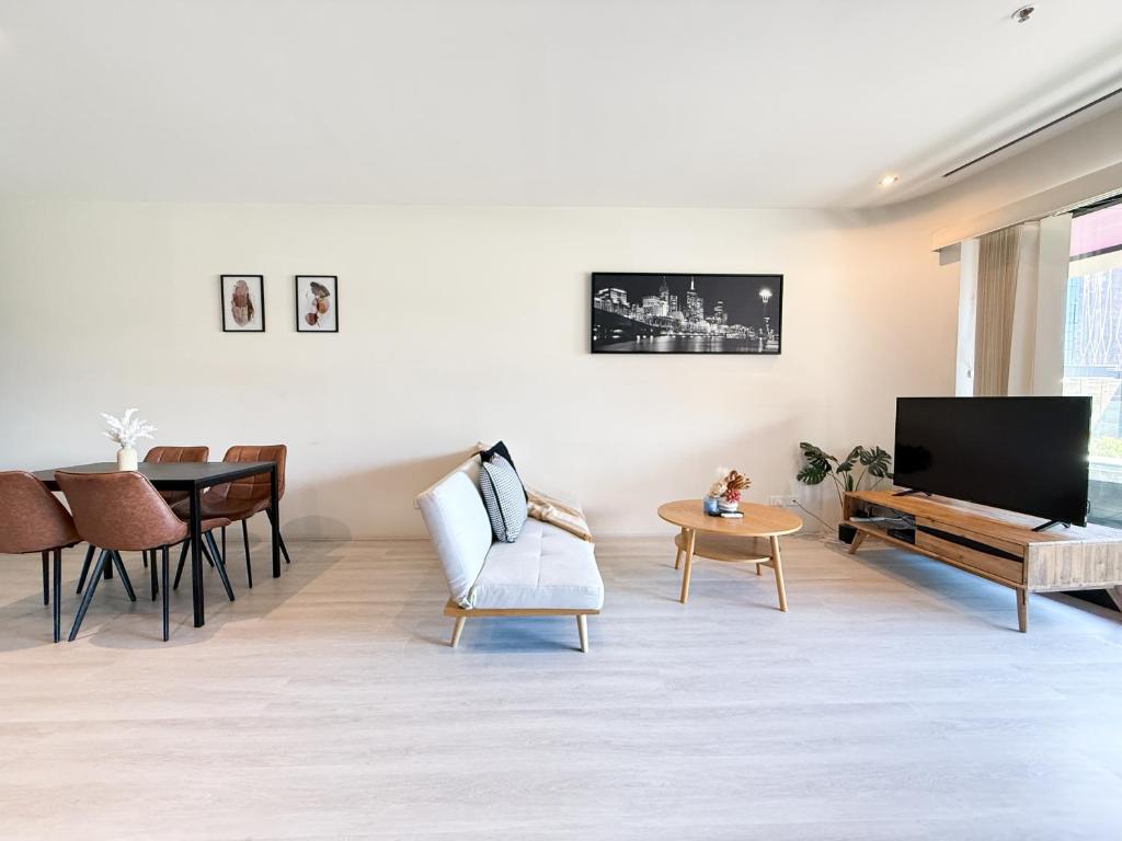 ein Wohnzimmer mit Fernseher und Tisch in der Unterkunft QV Spacious 2BR APT CityCentre State Library in Melbourne