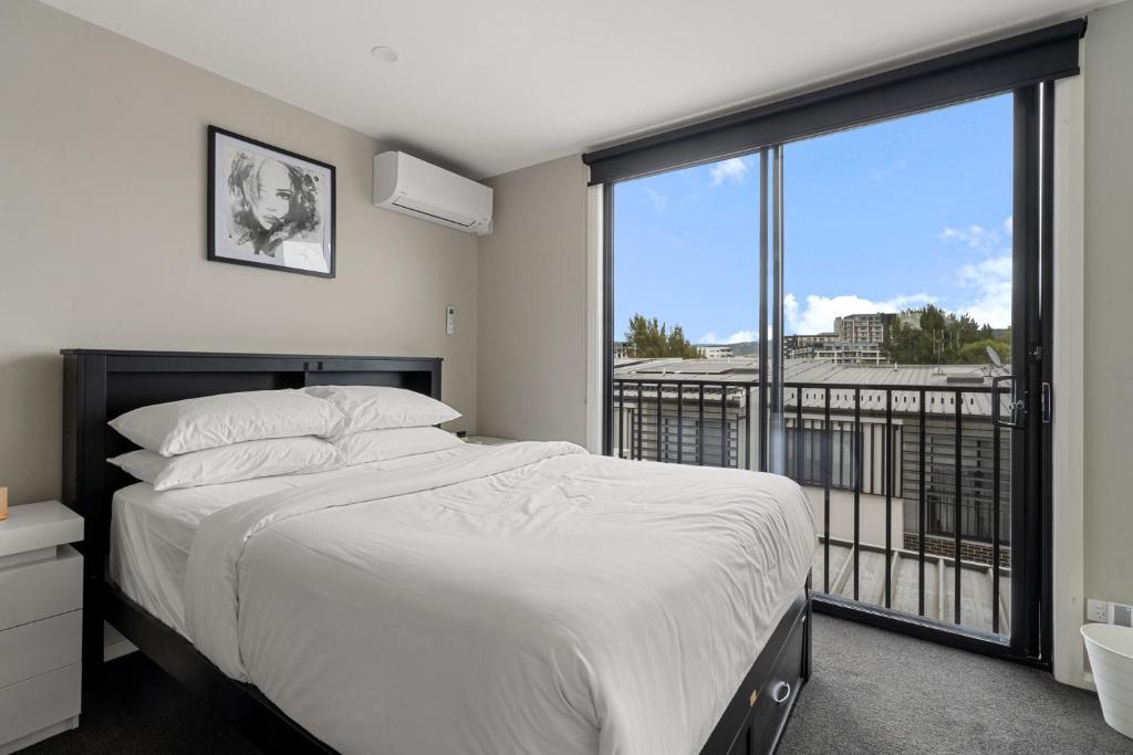 a bedroom with a bed and a large window at Modern 3-Bedroom Townhouse in Quiet Greenway in Tuggeranong