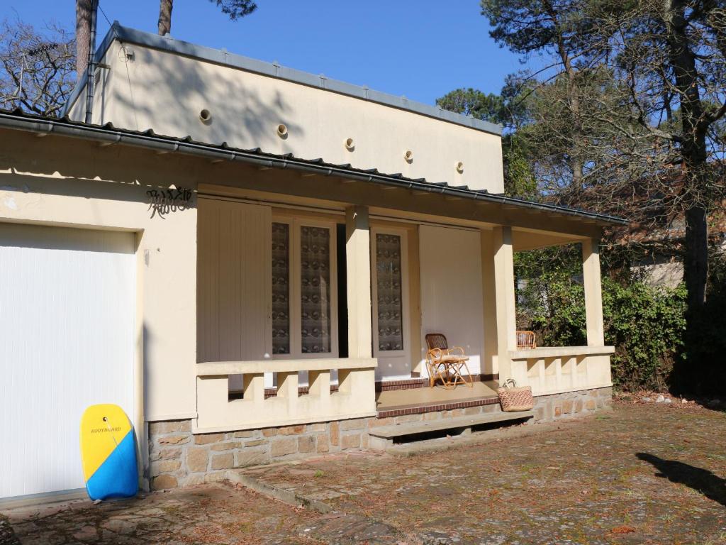 une maison blanche avec un chien assis sur le porche dans l'établissement Maison Brévinoise proche de la plage - 5 personnes - FR-1-364-81, à Saint-Brévin-les-Pins