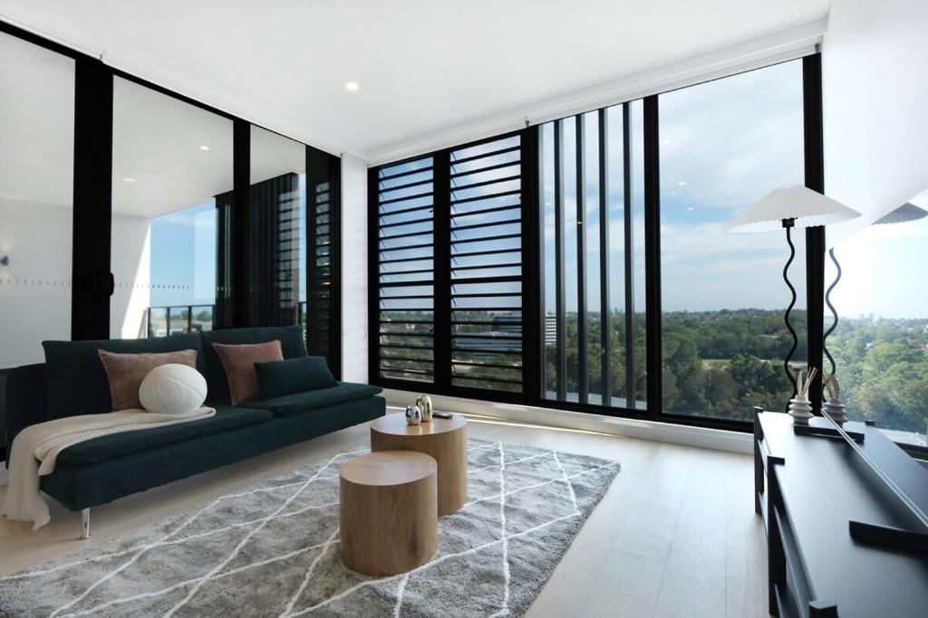 un soggiorno con divano verde e ampie finestre di MQ Lux 2BR Apartment with study, pool, free parking, Metro a Sydney